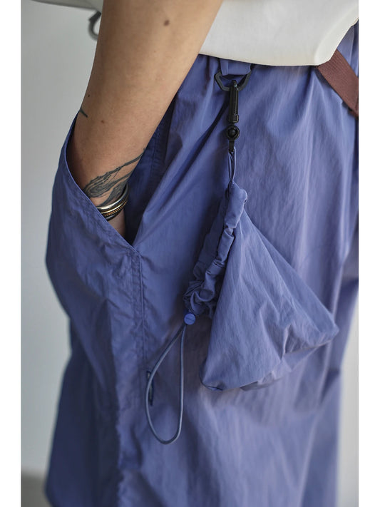 Person wearing a blue shirt with a white top underneath, standing against a plain background.