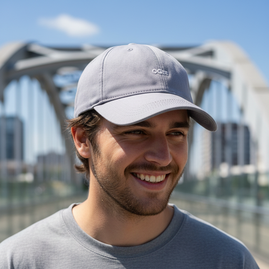 Man wearing a gray cap with 'OGEE' logo, standing in front of a bridge.