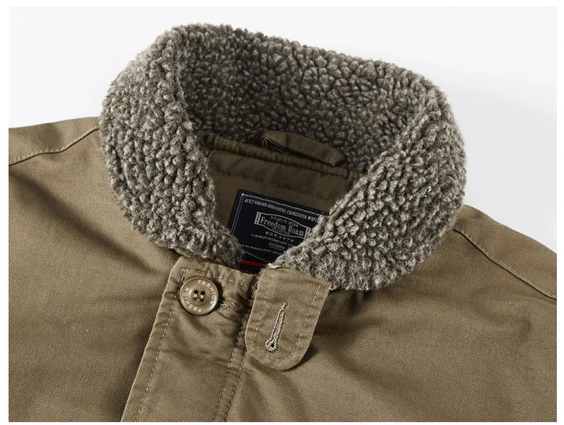 Close-up of a brownish-khaki jacket with a thick, textured gray sherpa fleece collar. A black and red interior neck label is visible, and a single button with a stitched metal tip is shown on the chest.