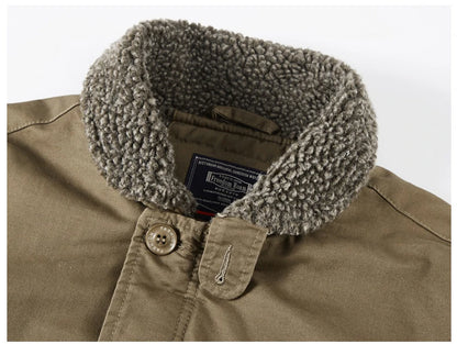 Close-up of a brownish-khaki jacket with a thick, textured gray sherpa fleece collar. A black and red interior neck label is visible, and a single button with a stitched metal tip is shown on the chest.