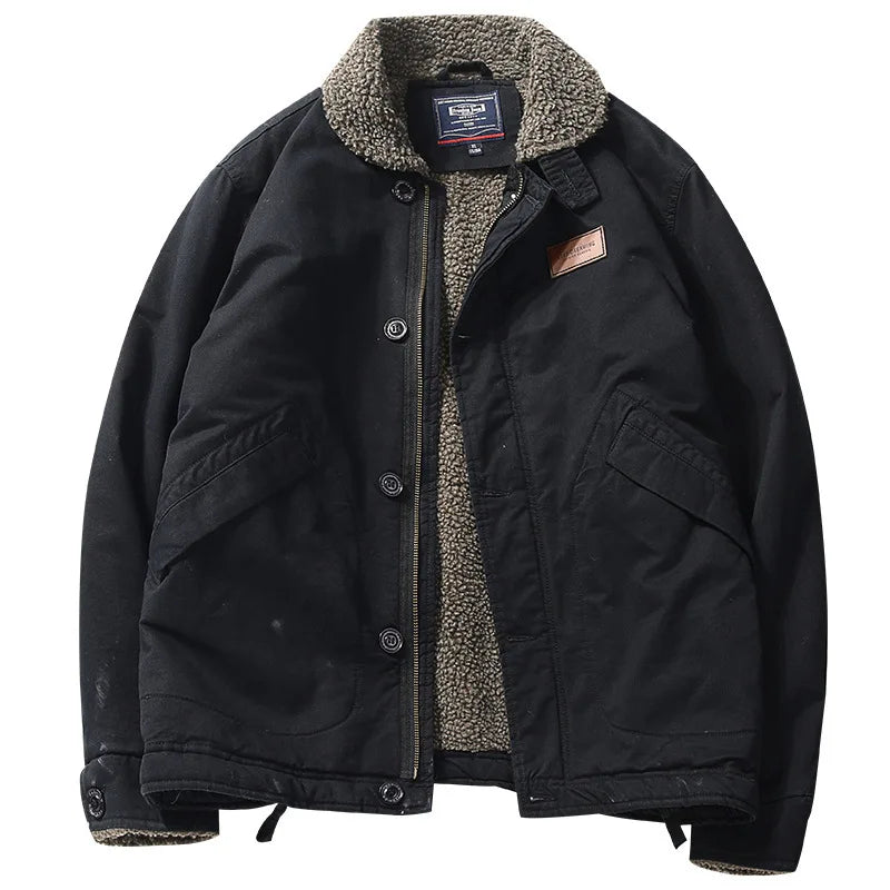 A black waxed canvas utility jacket with a warm gray sherpa fleece lining, featuring a button-up front, large front flap pockets, and a brown leather brand patch on the chest.