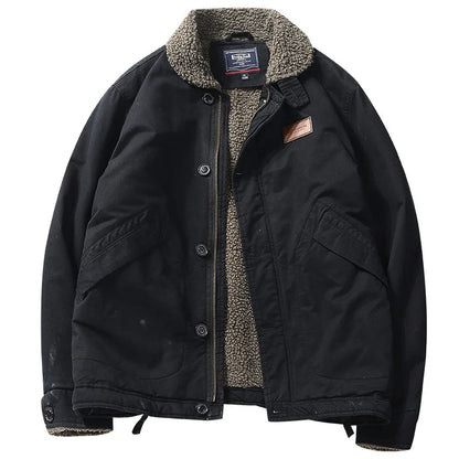 A black waxed canvas utility jacket with a warm gray sherpa fleece lining, featuring a button-up front, large front flap pockets, and a brown leather brand patch on the chest.