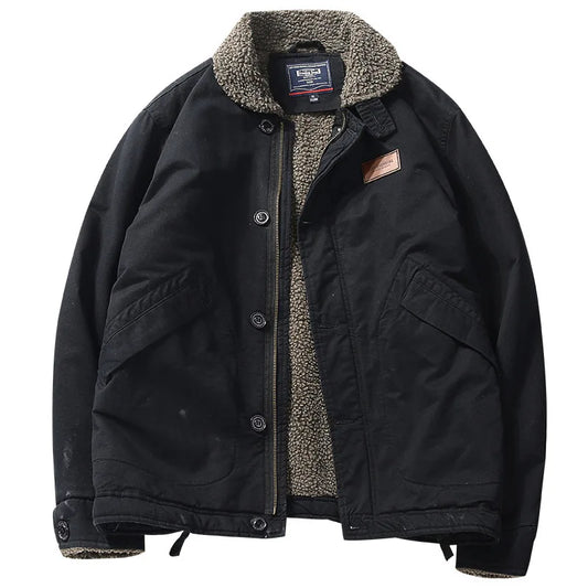A black waxed canvas utility jacket with a warm gray sherpa fleece lining, featuring a button-up front, large front flap pockets, and a brown leather brand patch on the chest.