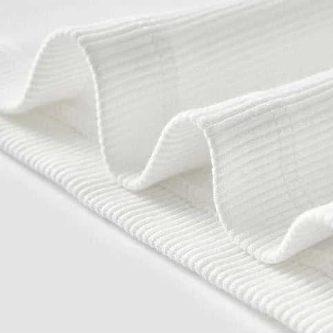 Close-up of a textured white blanket on a light gray background