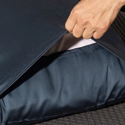 Person opening a navy blue garment bag with a white shirt inside.