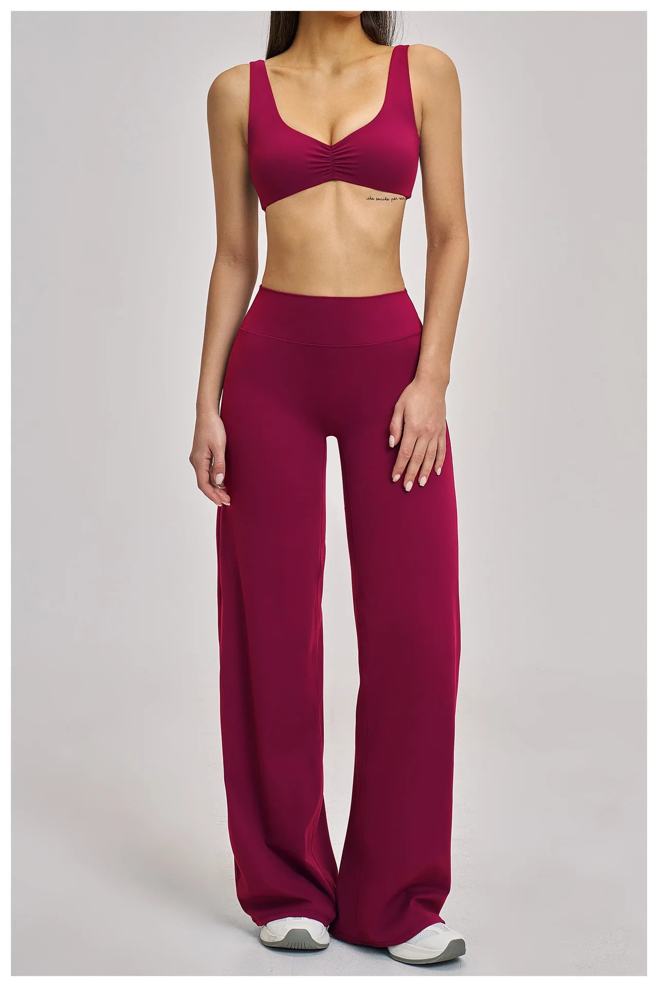 Person wearing a maroon sports bra and leggings on a plain background