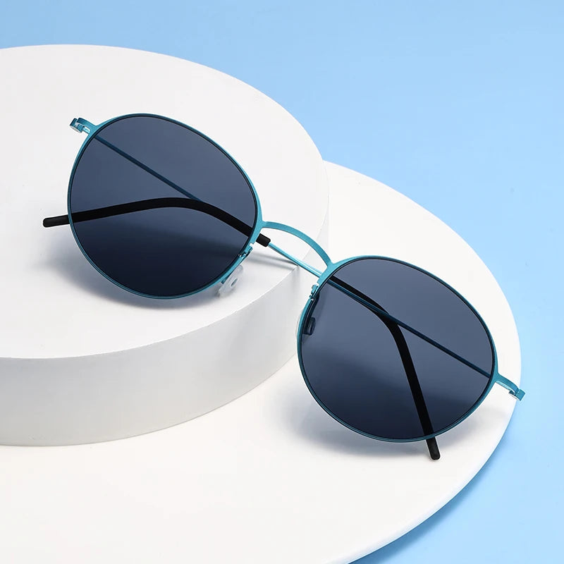 Round sunglasses with blue frames and dark lenses on a white surface with a light blue background