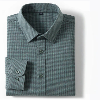 A folded long-sleeve button-down dress shirt in a muted blue-gray houndstooth pattern, featuring a classic collar and a buttoned cuff, displayed on a clean white background.