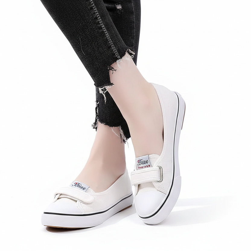 White sneakers worn with ripped black jeans on a white background