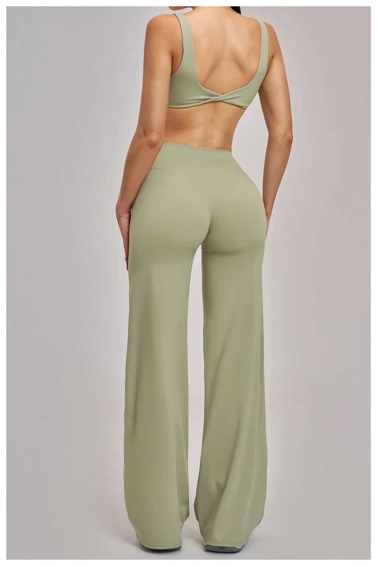 Person wearing a green sports bra and wide-leg pants on a light gray background