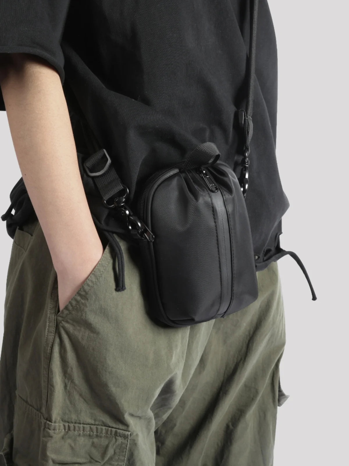 Person wearing a black bag over one shoulder with a plain background