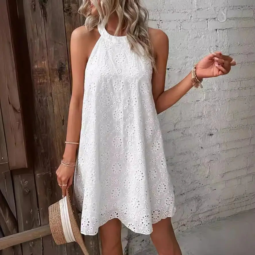 Woman wearing a white lace dress against a brick wall.