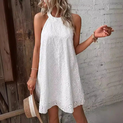 Woman wearing a white lace dress against a brick wall.