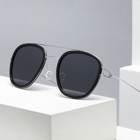 Black sunglasses with silver frames on a white surface against a light gray background