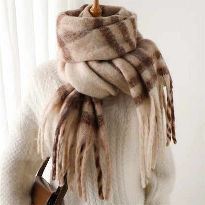 A thick, soft faux-fur scarf with brown and beige stripes and long fringe tassels, wrapped around a mannequin wearing a cream knit sweater.