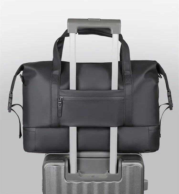 Black travel bag with a pull rod design attached to a suitcase on a light gray background.