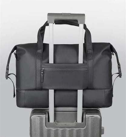 Black travel bag with a pull rod design attached to a suitcase on a light gray background.