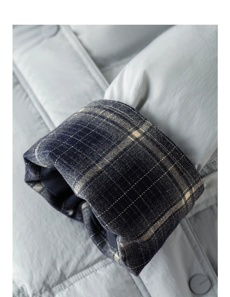 Close-up of a folded plaid lining or cuff in dark navy and beige tones, shown against a light gray quilted fabric background.