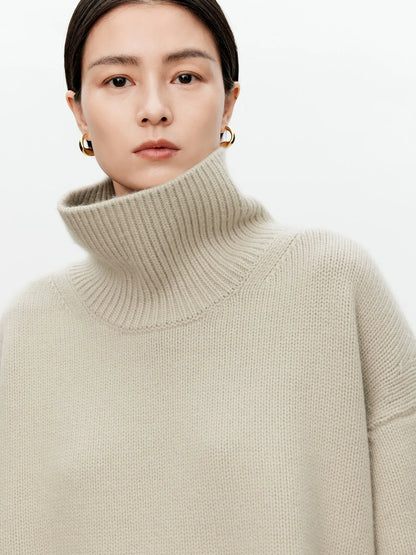 Person wearing a beige turtleneck sweater against a white background