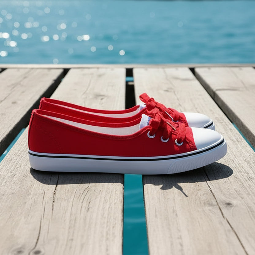 Red canvas shoes with white soles on a gray surface