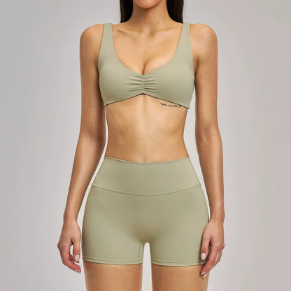 Person wearing a green sports bra and shorts set on a plain background