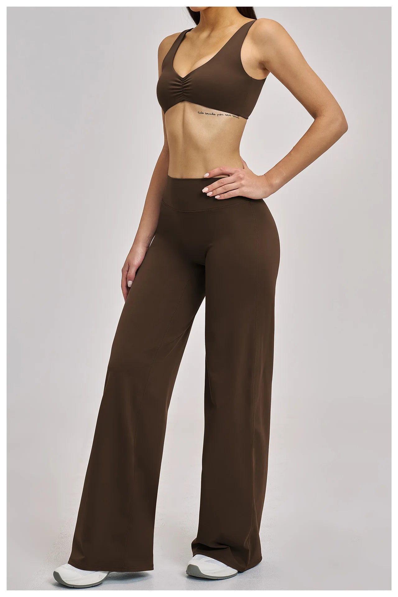 Woman wearing a brown sports bra and leggings on a gray background