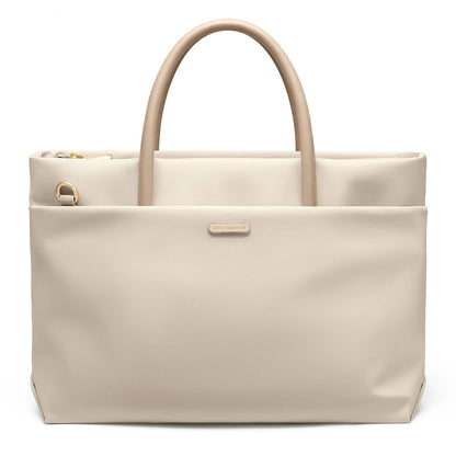 A light beige GOLF tote bag with dual top handles, a front slip pocket, and a small metallic brand plaque, shown on a white background.