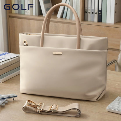 A structured beige tote bag with dual top handles and a detachable shoulder strap, displayed on a wooden desk with books and binders in the background. The brand name GOLF is visible in the top left corner.
