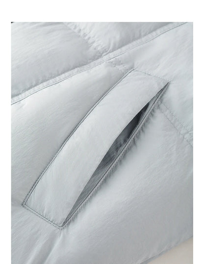 Close-up of a light gray puffer jacket showing a padded zippered pocket with stitched flap detailing.
