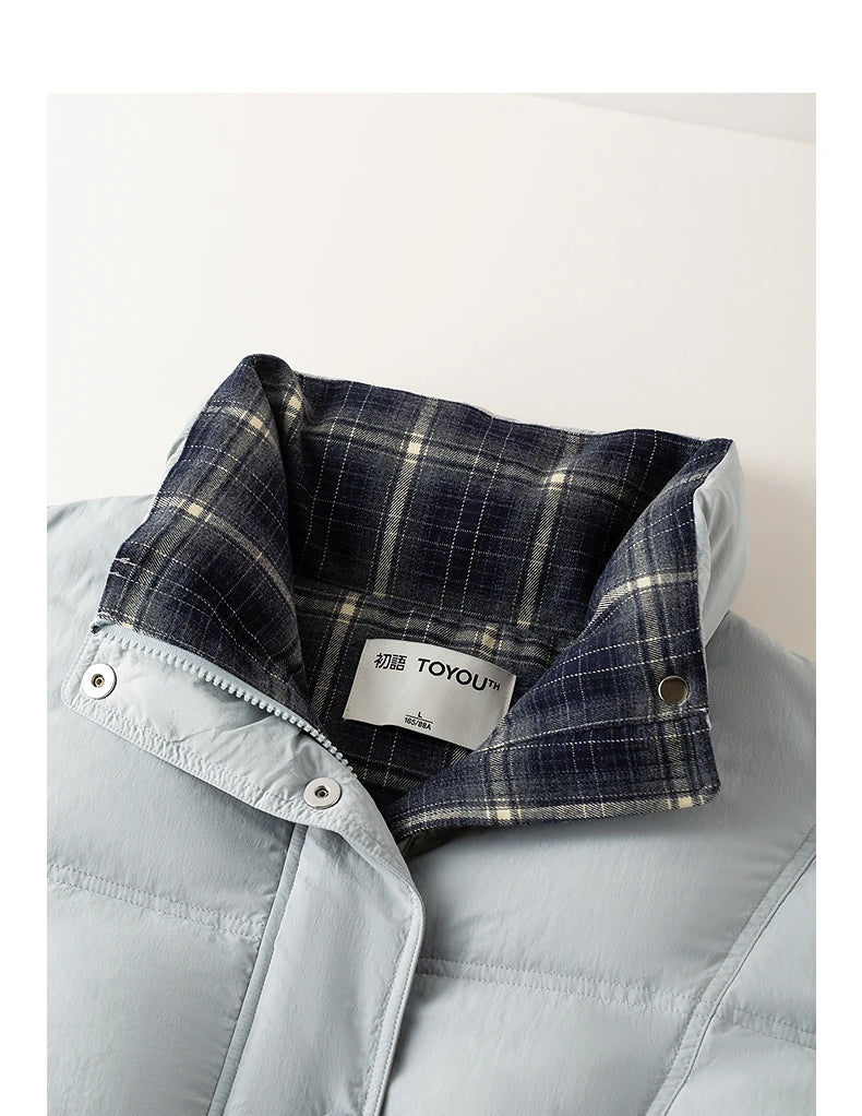 Close-up of a light blue puffer jacket with a folded collar showing a navy and beige plaid lining. A white brand label reading TOYOU is visible inside the collar.