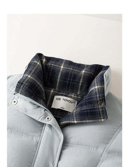 Close-up of a light blue puffer jacket with a folded collar showing a navy and beige plaid lining. A white brand label reading TOYOU is visible inside the collar.