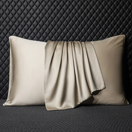 Two beige satin pillows on a textured black background
