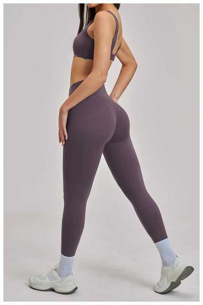 Person wearing purple athletic leggings and sports bra on a light gray background
