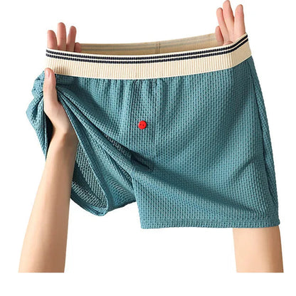 Teal cotton fashion pants held up by a person on a white background