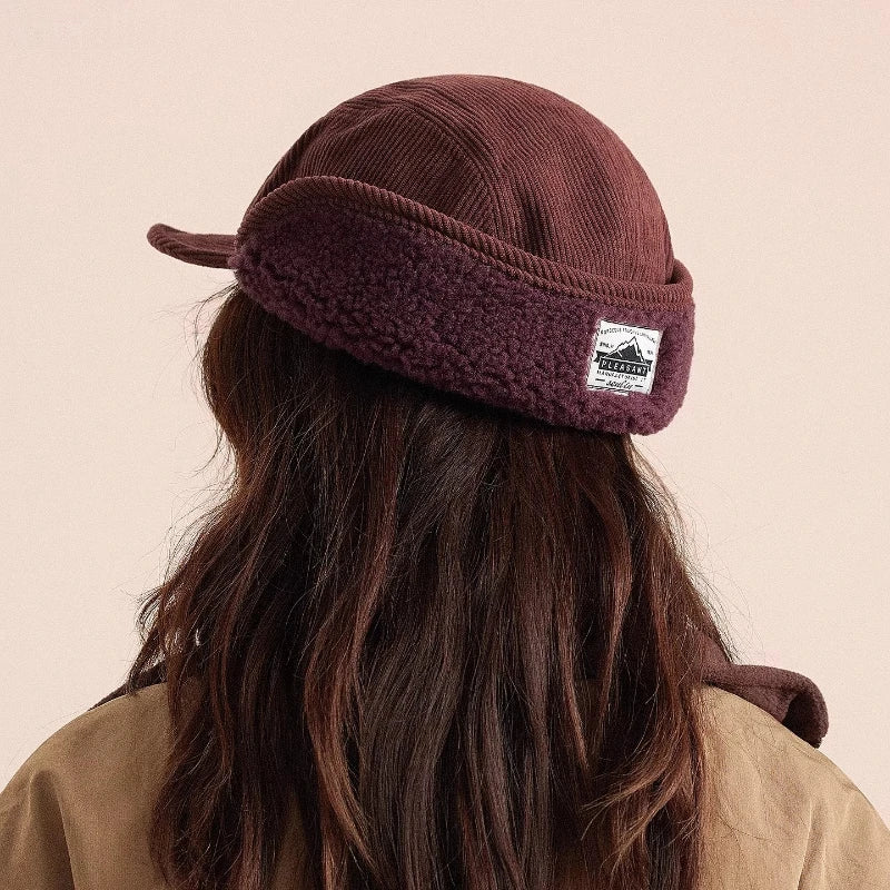Brown knitted headband with a logo worn by a person on a beige background